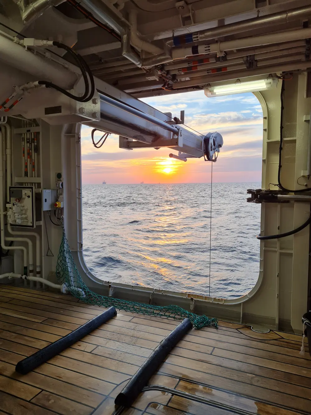 Sunset over the sea viewed through the open sampling deck of a research vessel